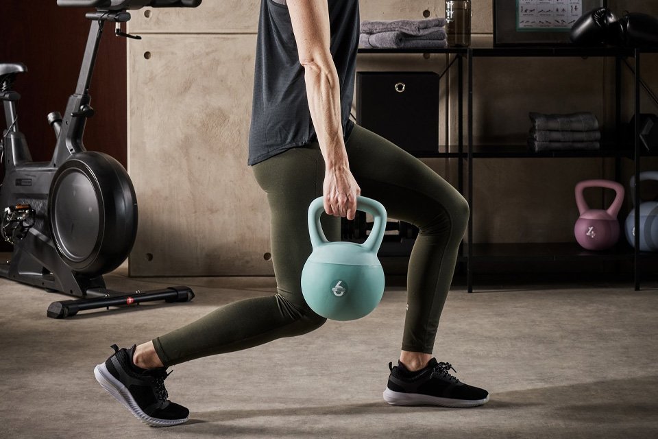 A woman using a Pro Fitness 6kg soft kettlebell.